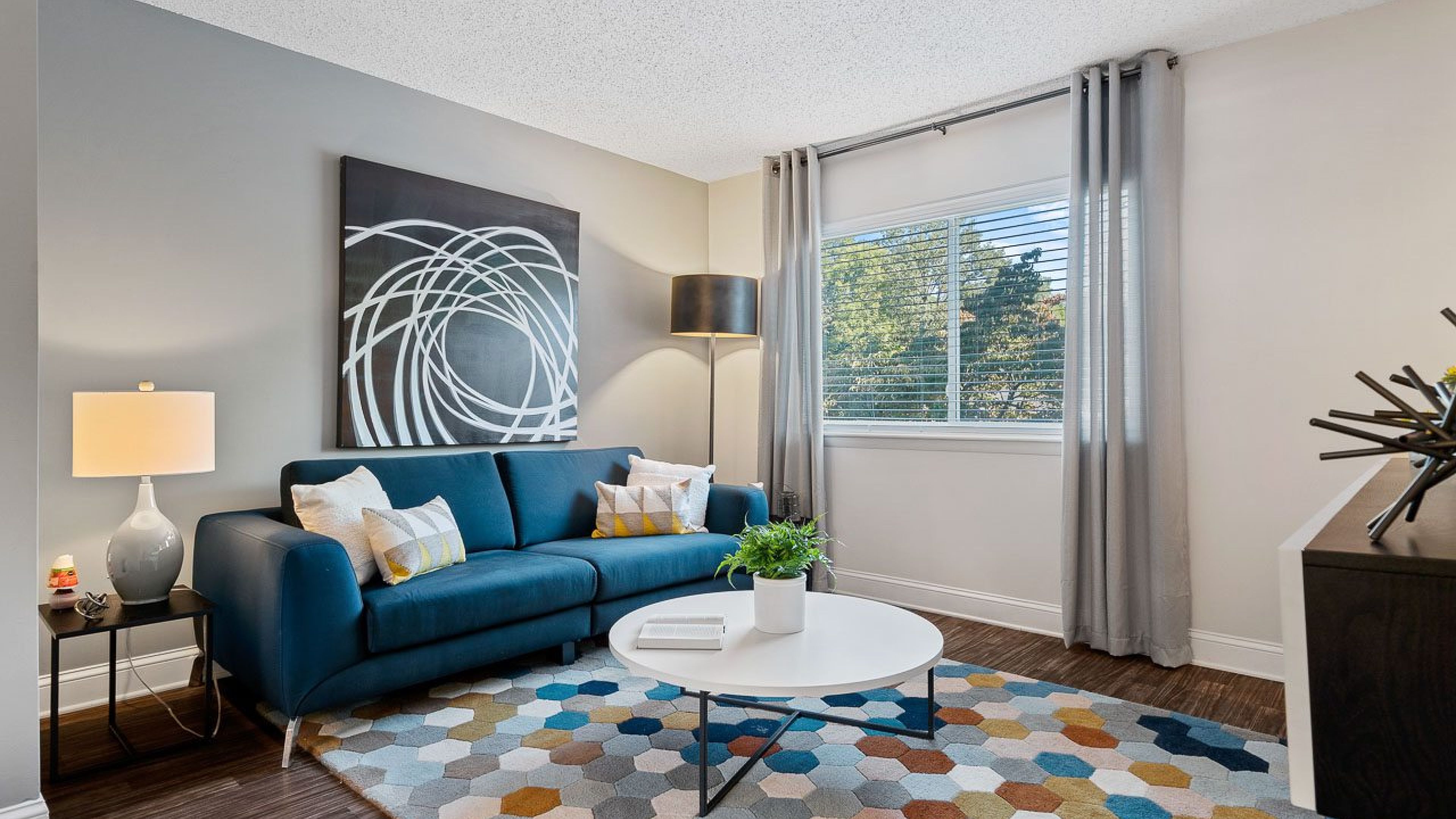 Hawthorne at Bear Creek apartment living room with large windows, furnished with a couch, coffee table, and end table